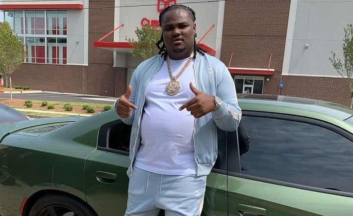 tee grizzley standing next to a green car