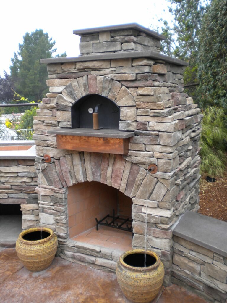 water running down two ceramic pots from an outdoor fireplace with pizza oven