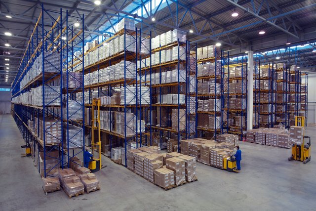 workers using forklift to carry up goods to different levels on a pallet shelve